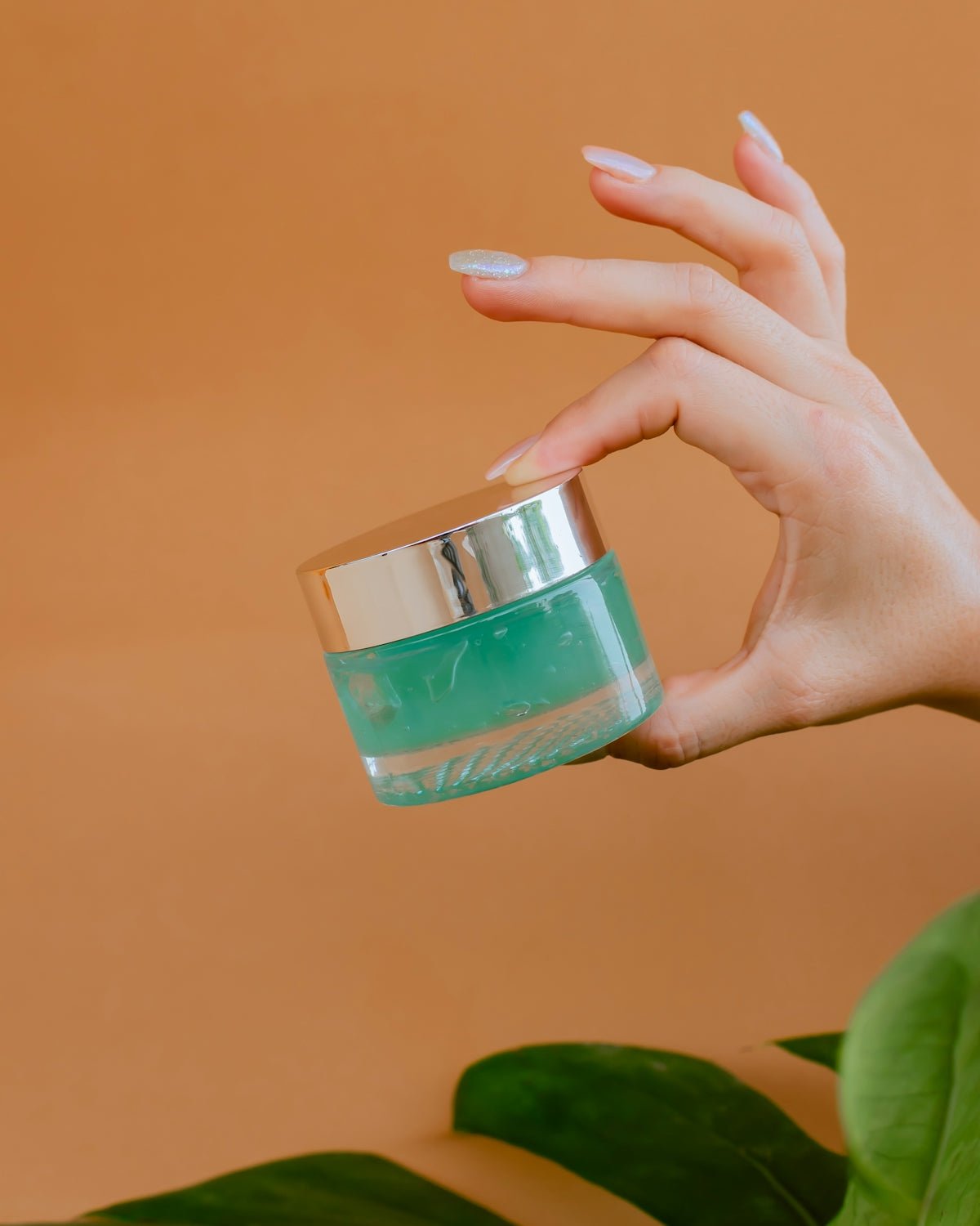 person holding clear glass bottle with green liquid